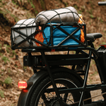 A RadRunner range extender installed on a green ebike which has a basket mounted on it holding camping gear. 